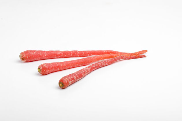 串新鲜的红色胡萝卜串在白色的表面食物素食叶子
