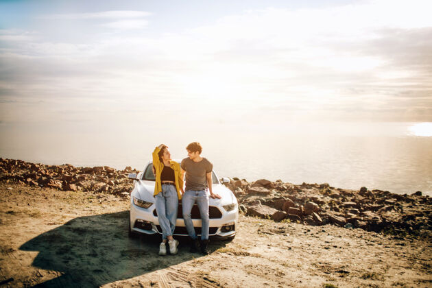 爱情一对浪漫的情侣站在路边一辆肌肉车旁海滩海滩英俊的胡须男和迷人的年轻女子有一段爱情故事女性海洋汽车