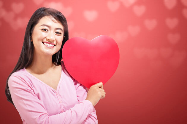 在一起一个亚洲女人拿着一颗红色的心墙情人节礼物天哪年轻情人节关系