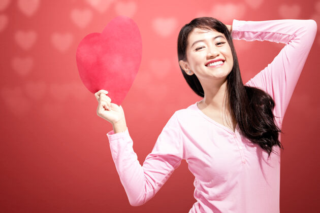 团聚一个亚洲女人拿着一颗红色的心墙情人节礼物天哪欢呼约会情人节