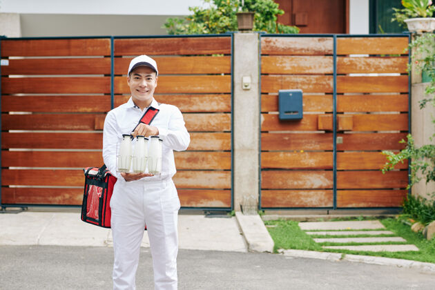 户外积极年轻的亚洲送货员穿着白色制服拿着铁丝牛奶箱男人新鲜乳制品