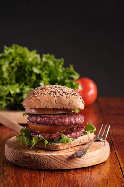 经典双层汉堡配番茄和生菜 放在一个朴素的木制底座上没有人肉快餐