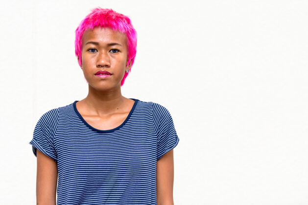 现代年轻叛逆的亚洲女人的肖像 粉色的头发映衬着白色的空间时尚穿孔古怪
