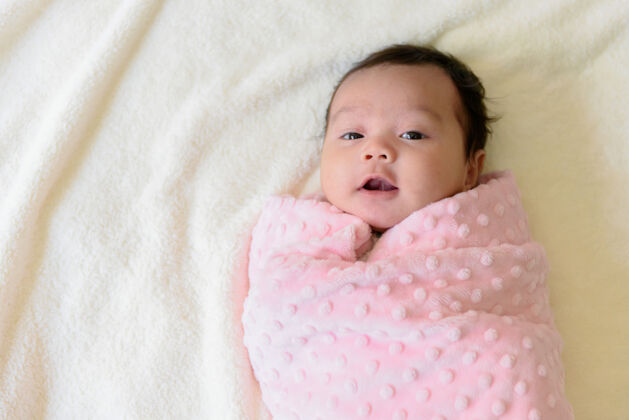 柔软床上裹着粉色布的可爱亚洲女婴的俯视图生活爱亚洲