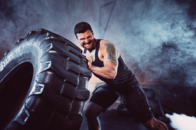 运动员健美训练 大胡子强壮的运动员 肌肉发达的身体举起沉重的轮子在健身房举重身体男子