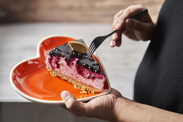 食物情人节戴女人从心形盘子里拿一片野莓老鼠蛋糕盘子情人节巧克力