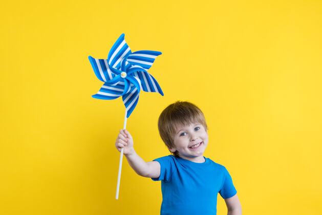 游戏孩子抱着玩具风轮机对着黄色的表面复制空间能源儿童