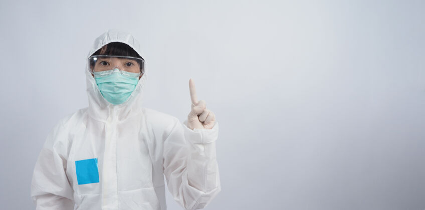 个人防护装备医生手势穿着ppe套装或个人防护装备的亚洲女医生手势和指点外白医用橡胶手套 护目镜眼镜和绿色n95口罩保护大流行的冠状病毒手眼镜病人