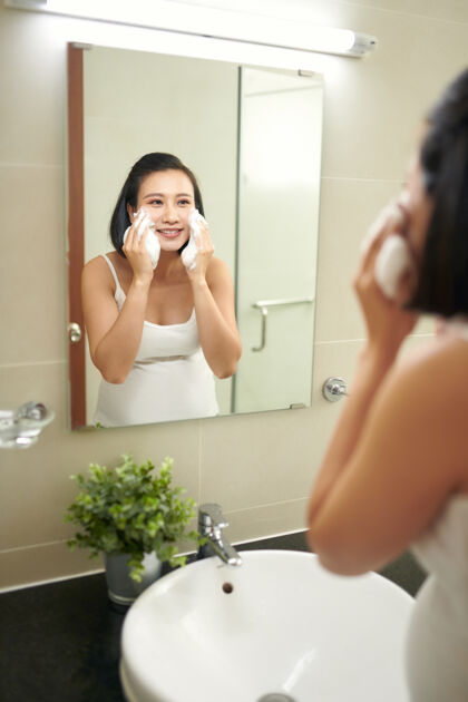 皮肤护理美丽的孕妇在浴室洗脸房子镜子脸