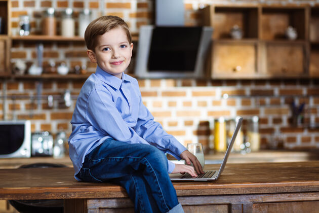 用户快乐的小男孩在厨房里休息 在网上冲浪情绪食物父母