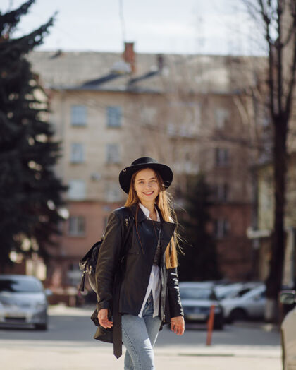 身体一个年轻漂亮的女孩微笑着摆姿势在城市里走来走去走道汽车购物