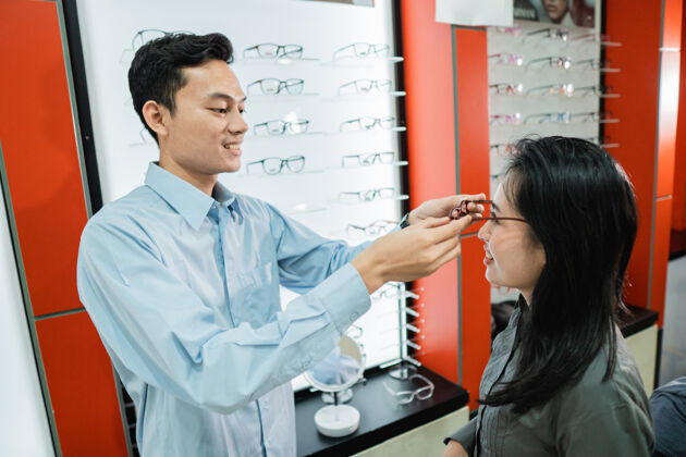 购买男店员在眼镜店给女顾客戴眼镜选择室内助理