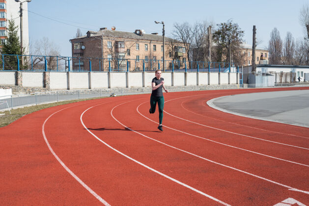 复制空间一个女人在体育场的跑道上跑步夏季健身锻炼跑步 运动 健康积极的生活方式女孩女草地