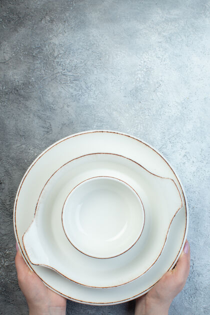 瓷手持白色餐具 置于半深-浅灰色表面的底部 表面凹凸不平容器半器皿