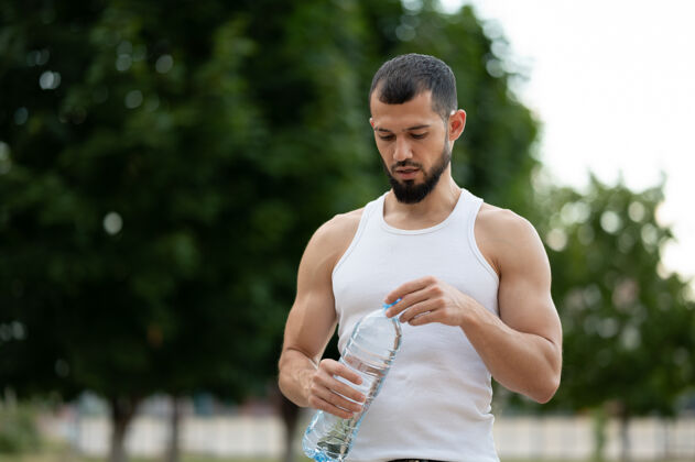 锻炼夏天在公园里喝水的运动型年轻人疲劳耐力水瓶