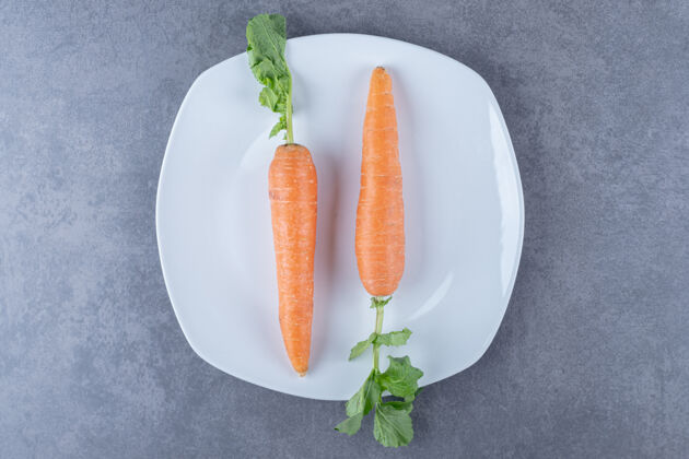盘子两个胡萝卜放在一个盘子里 放在大理石表面上胡萝卜好吃的生的