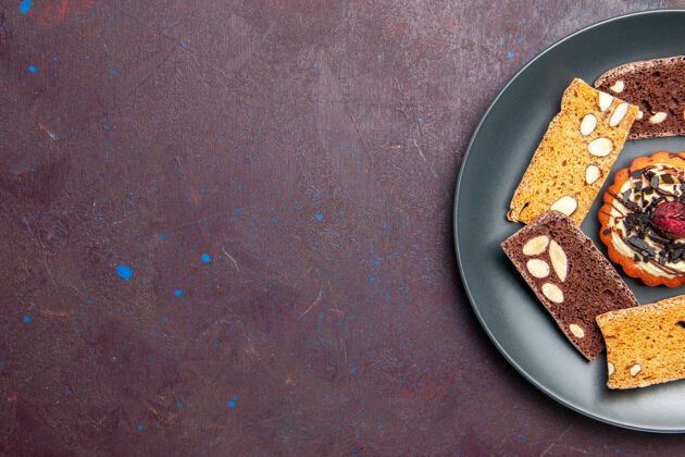盘子俯视图美味的蛋糕片与坚果和小饼干在黑暗的背景甜饼干甜点蛋糕饼干锅蛋糕