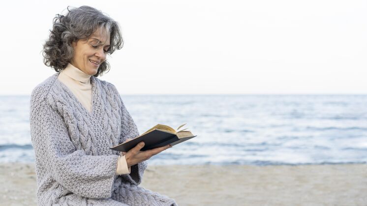 老年人海滩上的老太太在看书复制空间阅读老年人