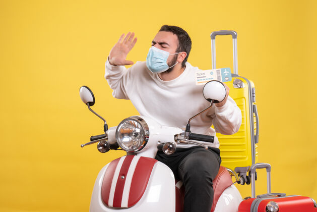 人旅行概念的俯视图 戴着医用面罩的年轻紧张的家伙坐在摩托车上人黄色抱