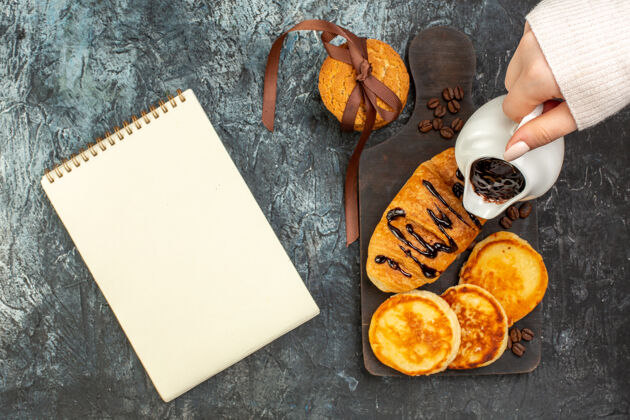 笔记本美味的早餐俯视图 薄饼 烤面包 饼干和笔记本堆在黑暗的表面上晚餐煎饼美味的早餐