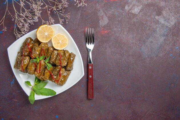 抹刀俯瞰美味的叶子杜尔玛与柠檬片在黑暗的背景肉菜叶子食物晚餐顶部叉子午餐