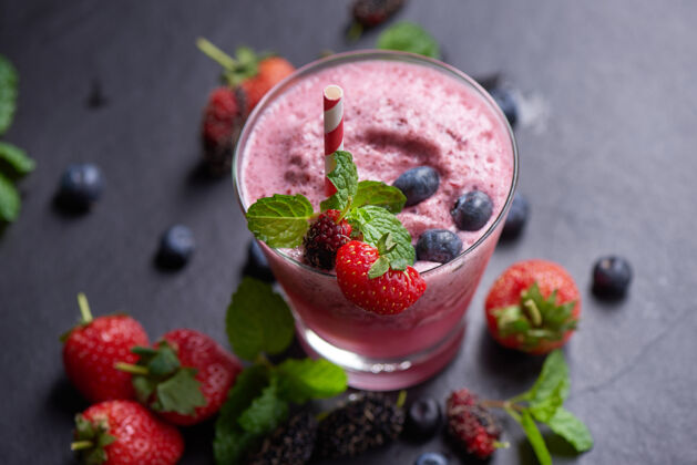 混合美味的草莓 桑葚和蓝莓冰沙点缀着新鲜的浆果和薄荷柔和的焦点美丽的开胃品粉色覆盆子 健康和减肥的概念营养多汁的玻璃