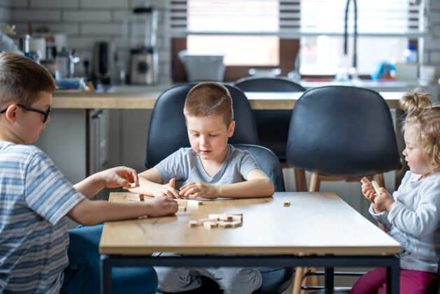 手小孩子在家里的厨房里用木块玩棋盘游戏木头桌子小