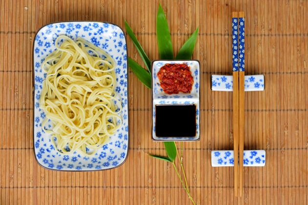 酱汁高角度拍摄的面条和酱汁在白色的盘子和筷子在一个竹制的桌面上家用角度传统