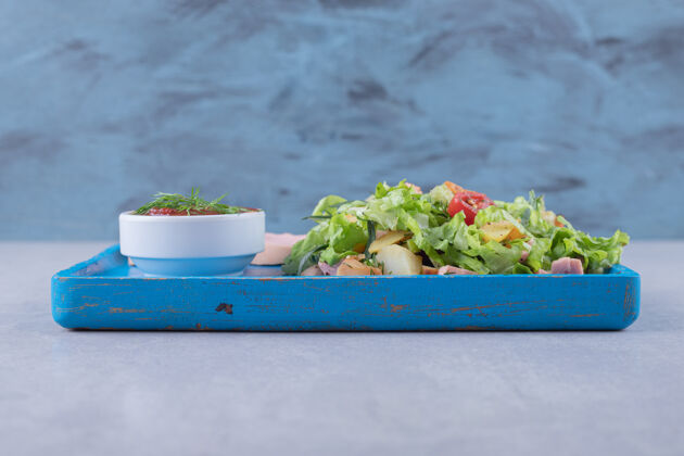肉新鲜沙拉和煮香肠放在蓝色盘子里食物晚餐生菜