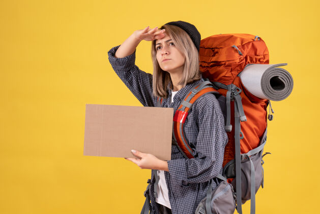 时尚背着背包拿着纸板的女旅行者可爱人纸板