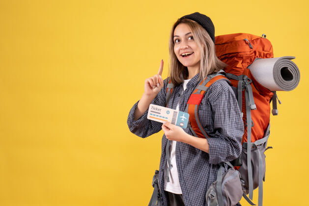 票面带微笑的旅行妇女背着背包拿着票 手指向上背包时尚黑发