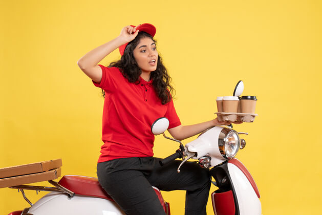 工作正面图骑自行车的女快递员拿着咖啡杯在黄色背景上服务制服工作女快递员工作人制服姿势