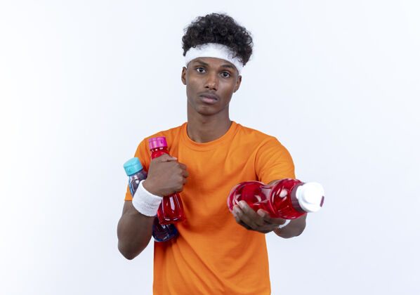 男人年轻的美国黑人运动男子戴着头带和腕带拿着水瓶对着镜头穿运动的瓶子