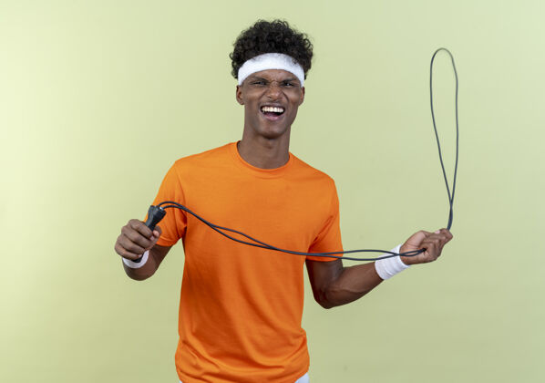 年轻快乐的年轻美国黑人运动男子戴头带和手环举行跳绳运动头带腕带
