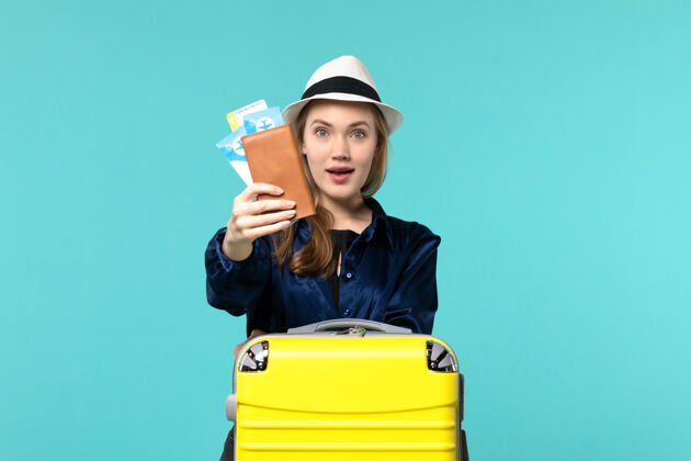 航行前视图年轻女子拿着机票 准备在蓝色背景下旅行海上度假旅行飞机旅行肖像微笑举行