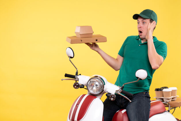 自行车正面图身着制服的年轻男性快递员手持黄色食品包装摩托车运输机服务