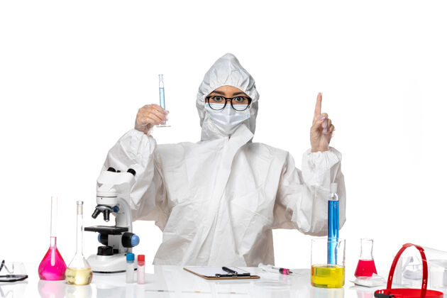 药品正面图身穿特殊防护服的年轻女化学家拿着白色背景的蓝色溶液烧瓶 实验室里有一种冠状病毒化学病毒外套化学套装