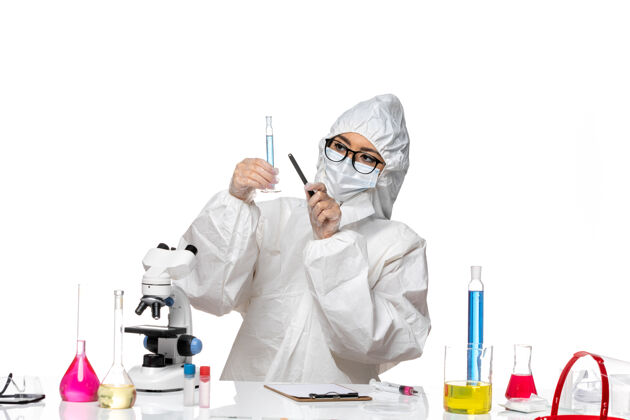 面罩正面图身穿特殊防护服的年轻女化学家拿着一个小瓶子 背景是白色的实验室冠状病毒化学病毒医疗特殊化学
