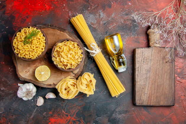 膳食各种生面食的顶视图 如大蒜柠檬油瓶和色彩斑斓背景上的砧板油食品传统