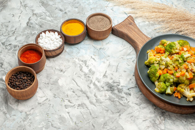 晚餐健康蔬菜沙拉白色背景上不同香料的顶视图容器勺子餐厅