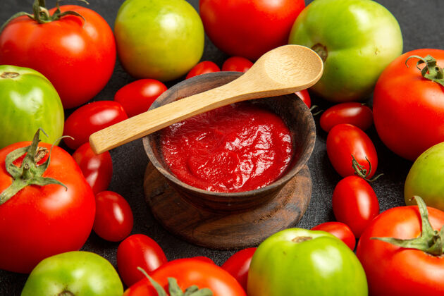 香草底部近距离观看樱桃红色和绿色的西红柿周围的一个碗番茄酱和一个木勺在黑暗的背景吃苹果饮食水果