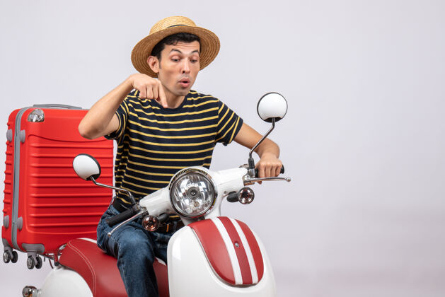 传送带一个戴着草帽的年轻人用手指指着摩托车的正视图帽子男人视图