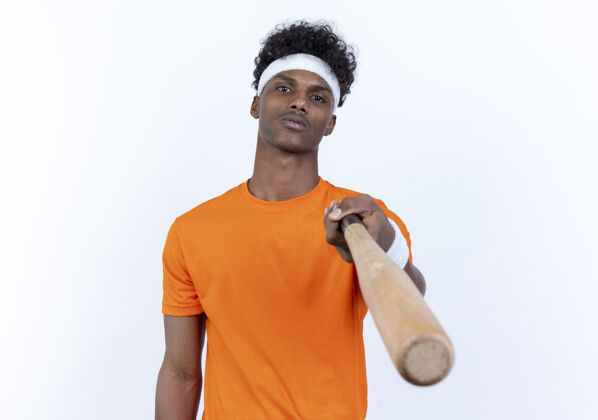 腕带自信的年轻美国黑人运动男子戴着头带和腕带拿着球棒对着镜头背景男人非裔美国人