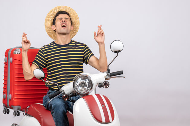 人年轻人戴着草帽坐在轻便摩托车上闭着眼睛许愿稻草摩托车轻便摩托车