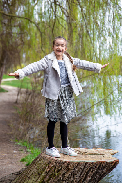 孩子一个有趣的小女孩在早春的森林里散步 享受大自然树桩湖泊自然