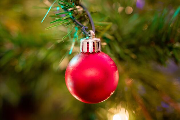 闪亮圣诞树上一个红球装饰的特写镜头背景明亮庆祝