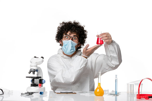 实验室外套正面图：男医生穿着防护服 戴着口罩 拿着白色背景上的红色溶液瓶专业实验室保持