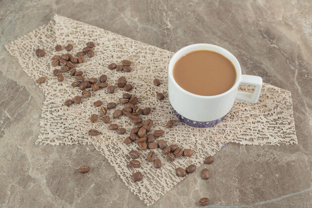 咖啡咖啡杯和咖啡豆在大理石表面与粗麻布豆类热浓缩咖啡