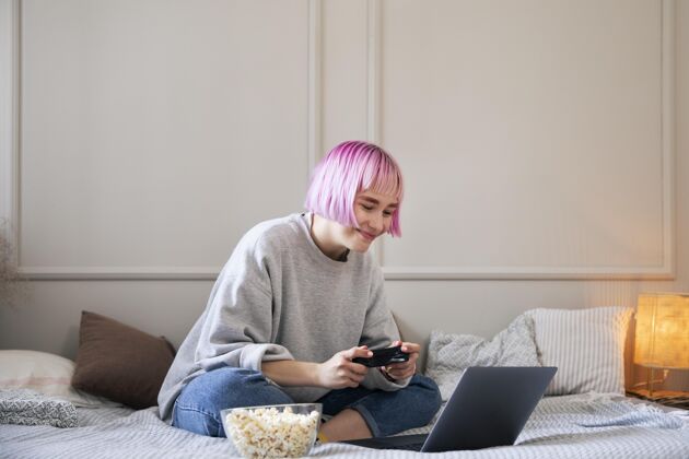 视频游戏粉红色头发的女人在玩笔记本电脑上的操纵杆技术玩家女人