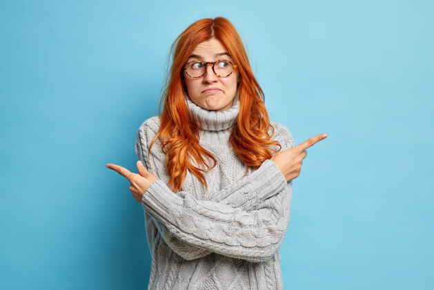 手指犹豫不决的红发女子双臂交叉在身体不同侧面或方向的部位 在两种选择中选择穿针织毛衣问题毛衣模特